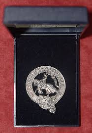 Photograph from above of a jewellery case with a pewter badge in it. The badge has a knight on horseback surrounded by a garter inscribed with Richard III's motto Loyaulte me lie