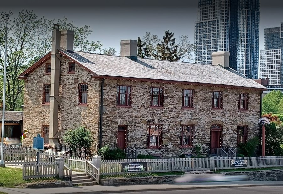 18th C Brick building with highrises in the background.
