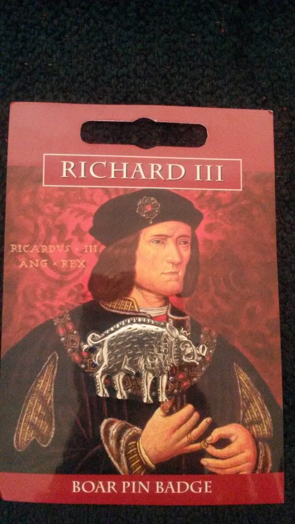 A silver coloured metal boar with a pin on the back.